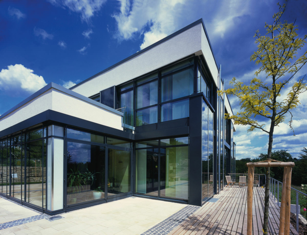 Ein Wohnhaus mit blauen Solarzellen in der Wand zur Stromerzeugung und mit Leichtpflegegläsern in Außenfenstern und -türen.