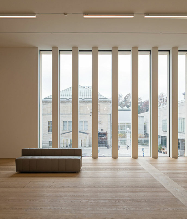 Großer Saal mit einer großen durch längs angeordnete Balken unterteilten Fensterfront und Holzboden