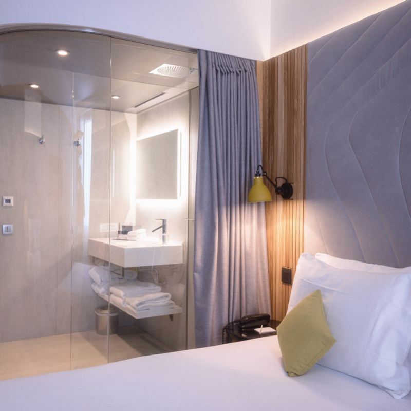 Hotelzimmer mit Bett und Dusche aus klarem gebogenem Glas