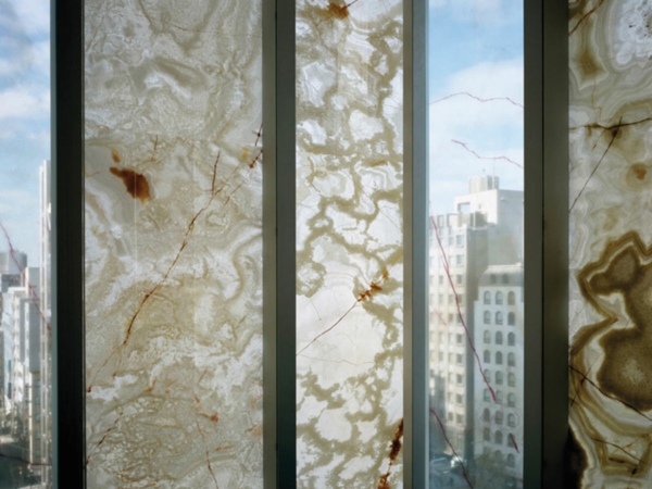 Fensterscheiben, längs zwischen Rahmen angeordnet, die halbtransparente Steindekore in beigebrauntönen zeigen.