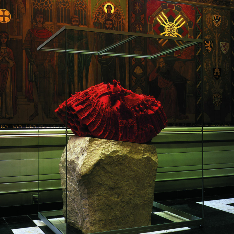 In einem dunklen Ausstellungsraum steht eine Vitrine, hinter dessen nahezu spiegelfreien Glas man ein Exponat aus Stein sieht.