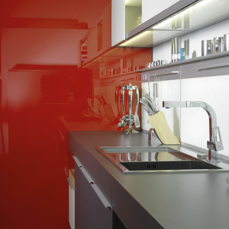 Küchenzeile, angrenzend an eine mit leuchtend rotem Glas verkleidete Seitenwand