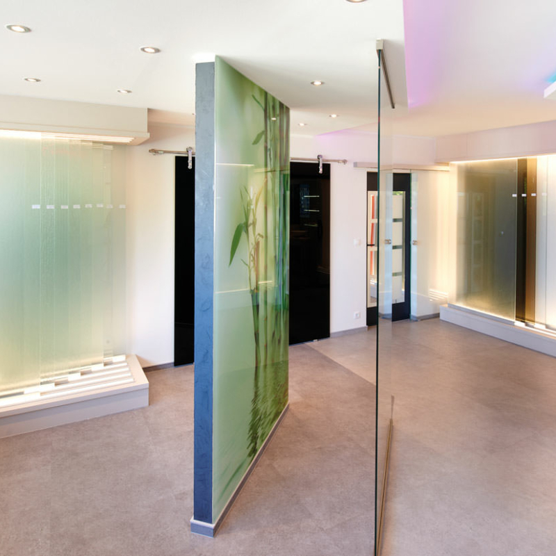 Ausstellungsraum mit schräg stehenden bedruckten, transparenten und farbigen Glasscheiben sowie links und rechts hinten jeweils in einer Halterung aufgestellten schmalen unterschiedlichen Glasscheiben.