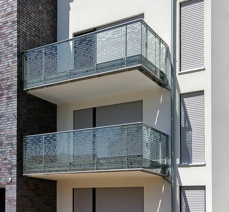 Teil einer Hausfassade mit zwei Balkonen mit gläsernen
