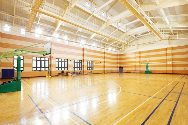 Blick über Eck in eine Sporthalle mit holzfarbenem Sporthallenboden