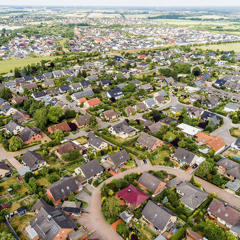Luftbildaufnahme eines typischen deutschen Neubaugebietes mit freistehenden Ein- und Zweifamilienhäusern in der Nähe einer größeren