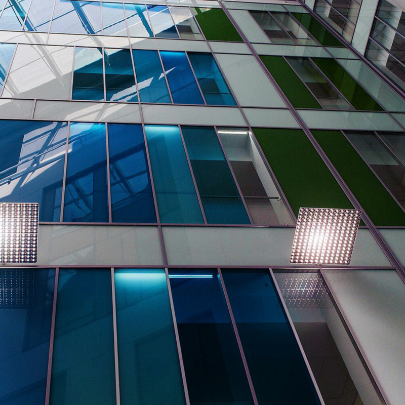 Ausschnitt einer Fassade mit Gläsern in unterschiedlichen Blautönen, Weiß, Grün und transparent.
