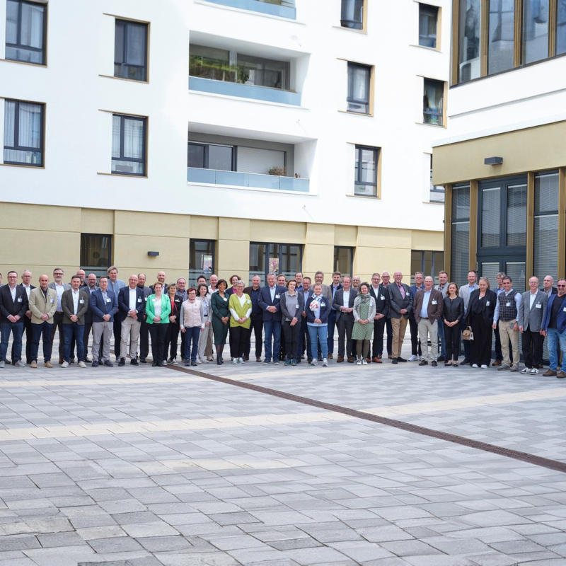 Viele Menschen sitzen an vier langen, gedeckten Tischen in einem weißen, hohen Rittersaal. Zwei Ritterrüstungen und ein knapp zwei Meter hoher Kerzenleuchter sorgen für mittelalterliches Ambiente.