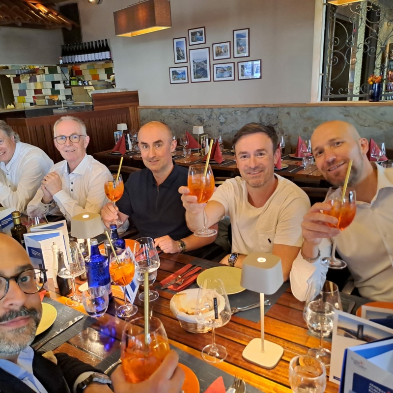 Eine Gruppe von Teilnehmenden der CLIMAplusSECURIT-Jahrestagung 2025 lächelt beim Abendessen und hebt gemeinsam ihre Gläser.